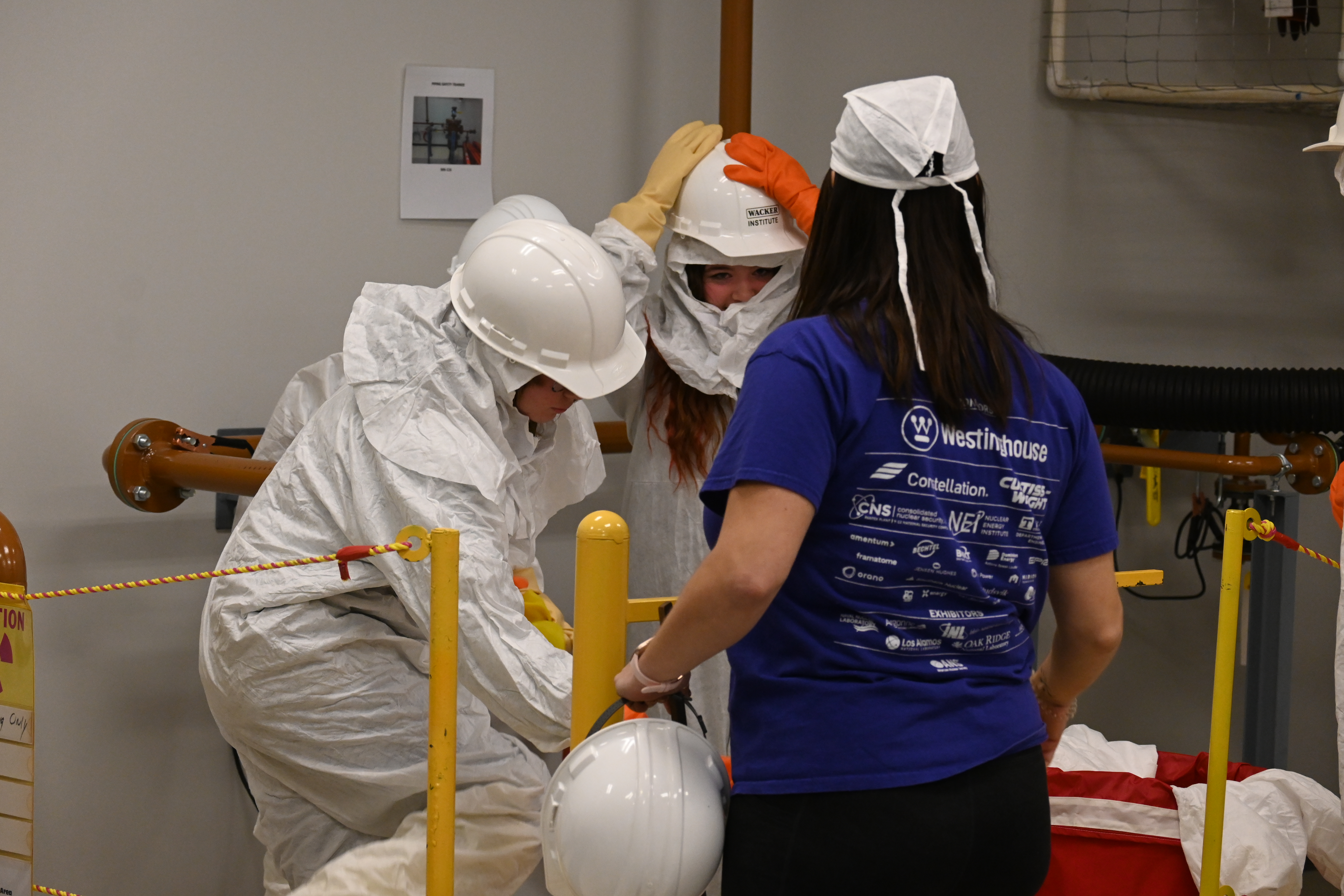 Girls practice removing radiation protection equipment during STEM Day 2025.