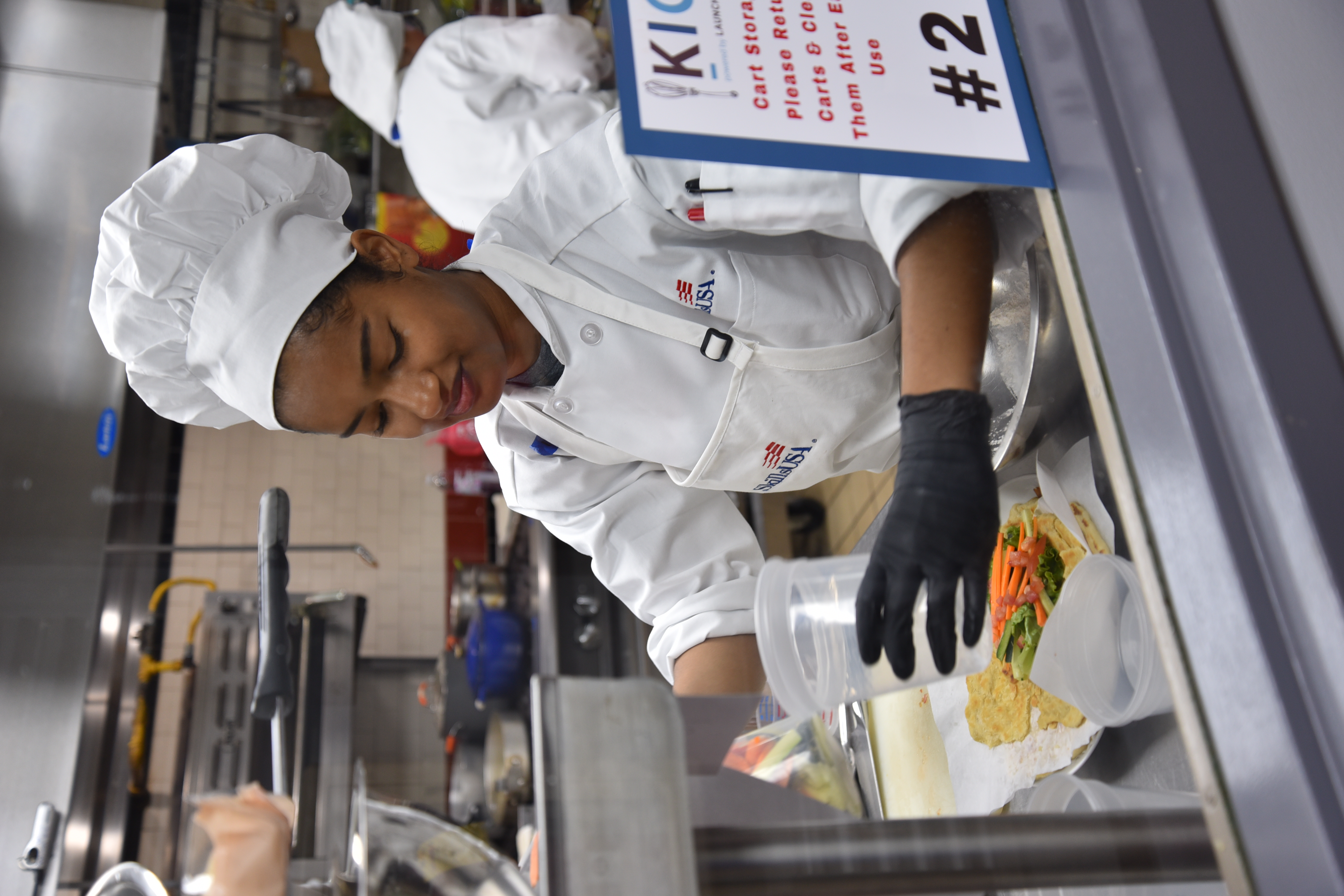 A SkillsUSA Culinary competitor in a chef's hat prepares food.