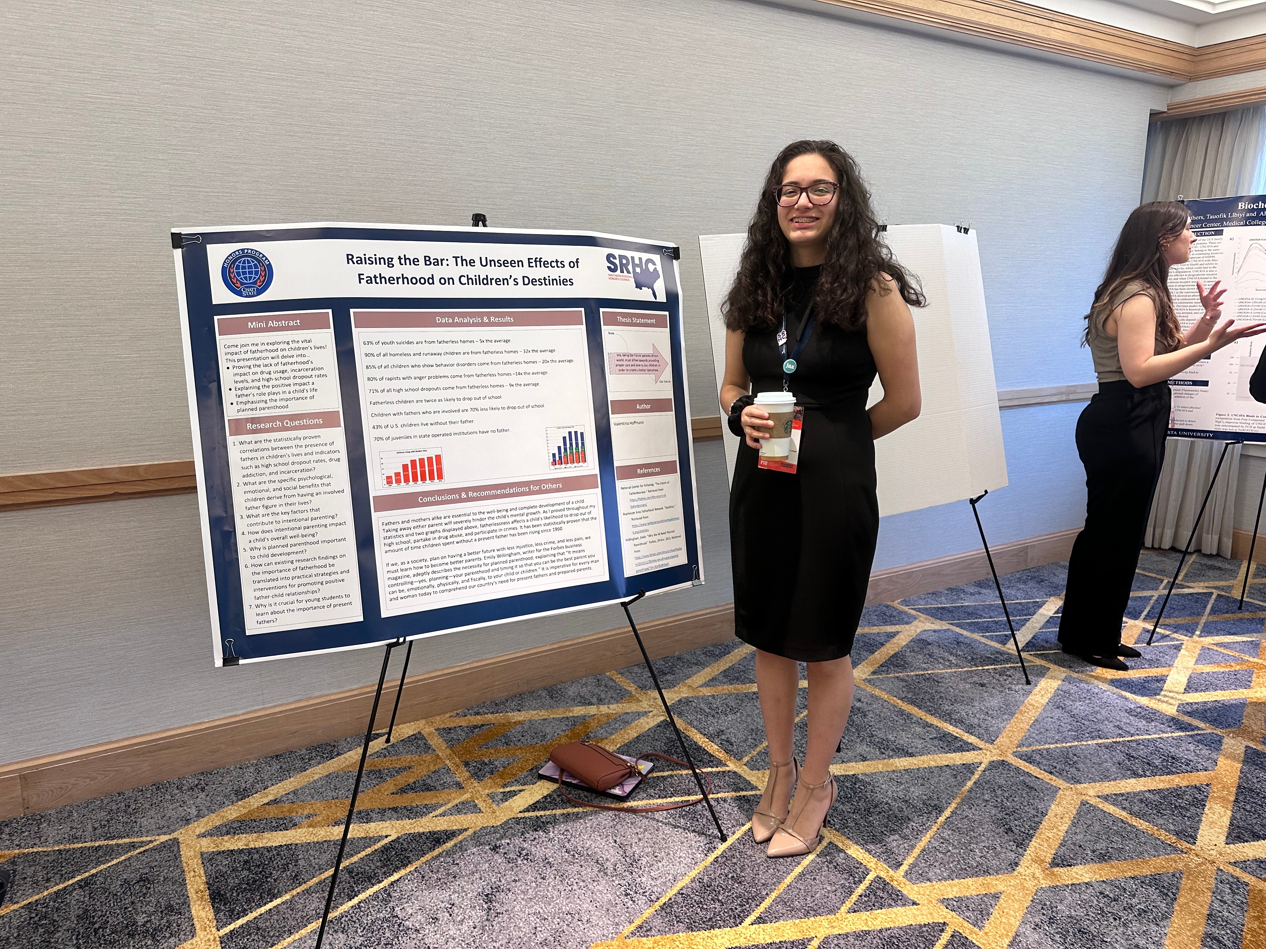 ChattState Honors student Valentina H. stands by a poster board for her presentation titled "Raising the Bar: The Unseen Effects of Fatherhood on Childrens’ Destinies."