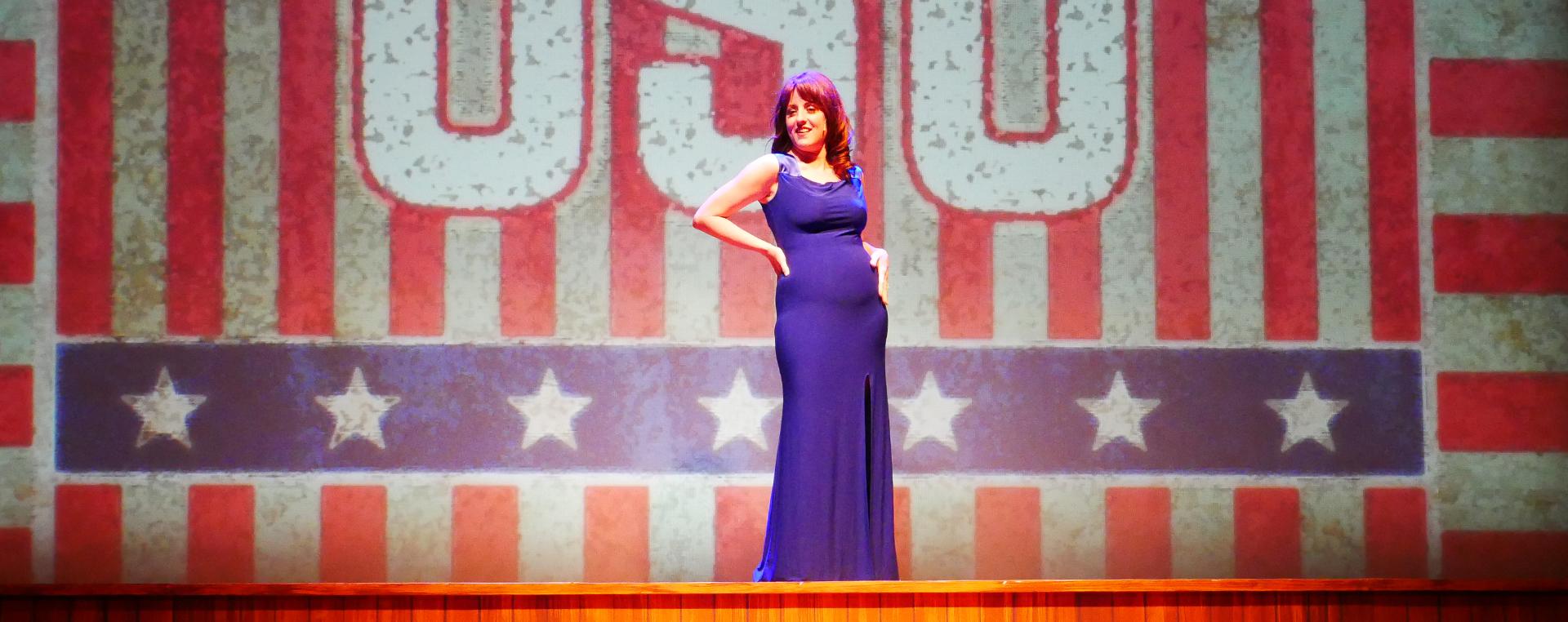 woman on stage in front of American flag backdrop
