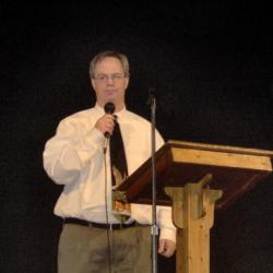 Photo of Dwight Hunter speaking at podium holding a mic