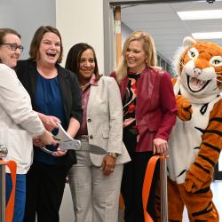 Heather Montgomery, Dr. Amanda Bennett, Dr. Martina Harris, Dr. Rebecca Ashford, and the Ben G. Tiger mascot cut a ribbon with large scissors in front of the Student Health Clinic at ChattState.