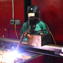 A young woman and an instructor look on at a welding machine.