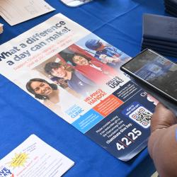 A woman uses her phone to scan a QR code on a ChattState Give Day poster. A woman uses her phone to scan a QR code on a ChattState Give Day poster.