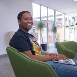 A student sits in a chair in the OMNI building at ChattState with a computer on his lap.