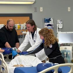 Respiratory care students gather around a medical mannequin.