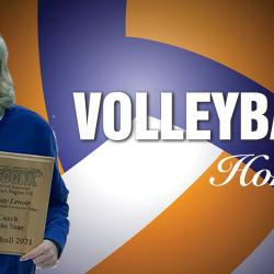 coach kristy lenoir with her award plaque on a volleyball ball background