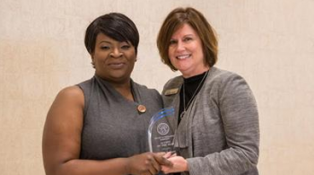 PTA program director Caroline Rogers (right) presents the PTA Alumni of the Year award to 2006 graduate and inventor of CPR Life Wrap to Felicia Jackson (left).