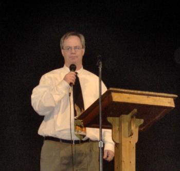 Photo of Dwight Hunter speaking at podium holding a mic