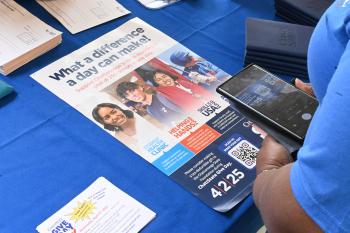 A woman uses her phone to scan a QR code on a ChattState Give Day poster. A woman uses her phone to scan a QR code on a ChattState Give Day poster.