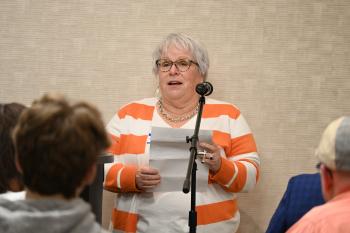 Sharon Butler speaks into a microphone. Sharon Butler speaks into a microphone.