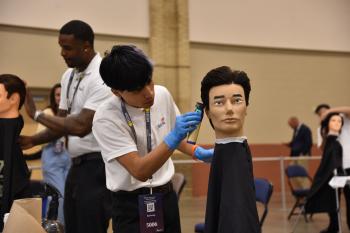 A SkillsUSA participant from ChattState cuts a mannequin's hair at the statewide SkillsUSA competition at the Chattanooga Convention Center in April 2024.