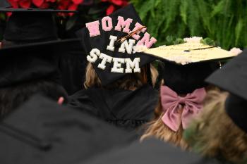 A woman wears a graduation mortarboard that reads "Women in Stem." A woman wears a graduation mortarboard that reads "Women in Stem."