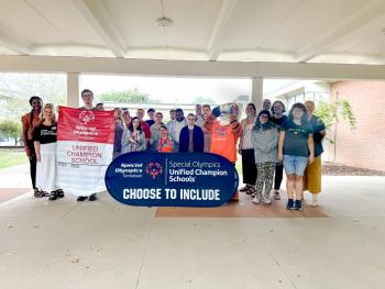 A group of students and ChattState's tiger mascot hold a sign that reads "Special Olympics Unified Champion Schools. Choose to include." 