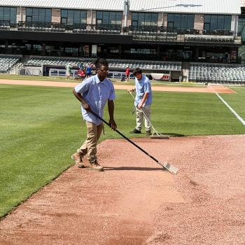 Landscape and Turf Management Two male students in workware use rakes to even out gravel on a baseball field.