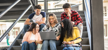 Several students look at a computer. Several students look at a computer.