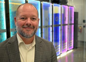 A man stands in front of colorful electronic panels.