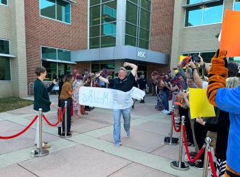 A SkillsUSA competitor from ChattState runs through a banner before boarding a bus to SkillsUSA nationals in Atlanta.