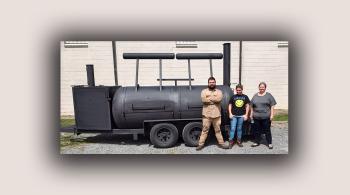 2 women and 1 man with bbq smoker they built in welding class